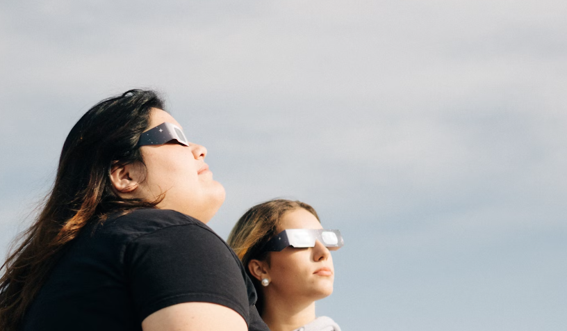 girls watching the solar ecplise with glasses
